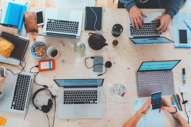 Business professionals working on laptops at a shared desk, symbolizing AI integration in daily operations.